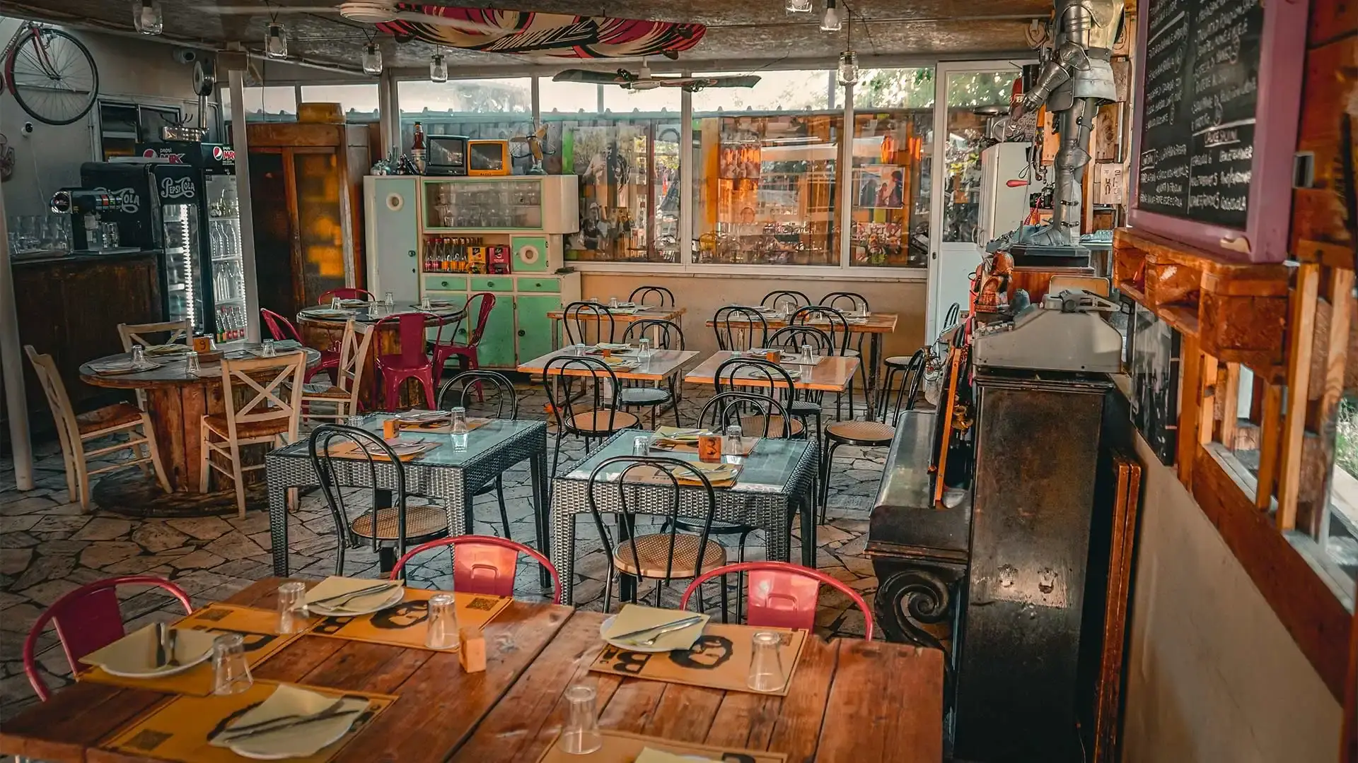 Interno della veranda del ristorante con tavoli apparecchiati e stile vintage